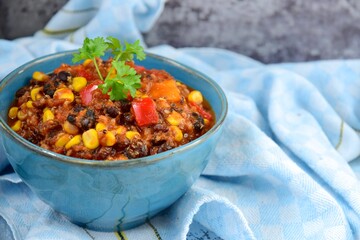 Black bean, quinoa, sweet potato, bell pepper and corn chili in a bowl garnish with parsley