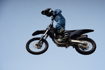 rider in a helmet makes a risky jump in the air on a black motorcycle