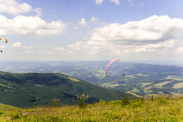 Paraglider soars in the sky against the background of blue mountains