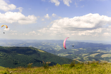 Paraglider soars in the sky against the background of blue mountains
