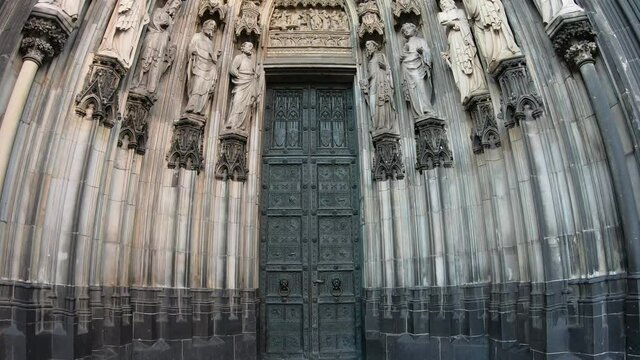 SLOW SHOT Entrance of the Cologne Cathedral (Kolner Dom), Roman Catholic cathedral, located in the city of Cologne, Germany, shows the 19th century decoration. Marble figures of saints on the facade.