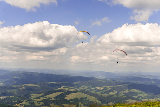 Paraglider soars in the sky against the background of blue mountains
