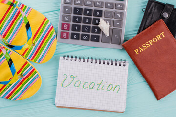 Top view of passport, sandals, calculator on table meaning for plan to travel in vacation. Vacation...
