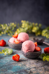 Strawberry ice cream in a bowl with fresh strawberries on blue background