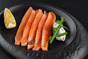 Freshly salted sliced salmon with lemon and curd cheese on plate