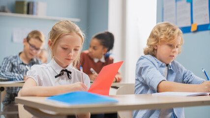 Elementary Classroom of Diverse Bright Children Listening Attentively to their Teacher Giving Lesson. Brilliant Kids in School Writing in Exercise Notebooks, Taking a Test. 