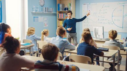 Caring Teacher Explains Lesson to a Classroom Full of Bright Diverse Children. In Elementary School...