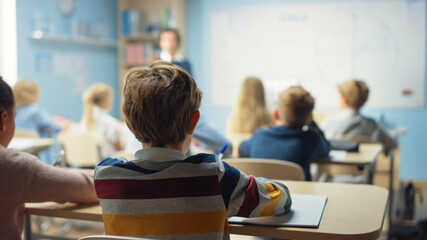 Caring Teacher Explains Lesson to a Classroom Full of Bright Diverse Children. In Elementary School...