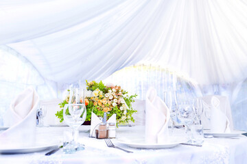 Wedding simple outdoor table setting in a white outdoor tent.