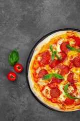 Pepperoni pizza with cherry tomatoes, cheese on black background