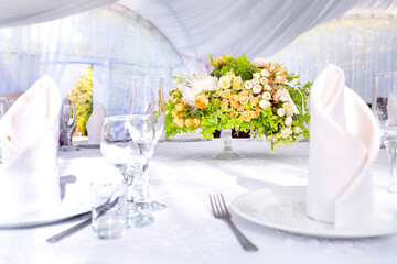 Wedding table with a white tablecloth in a white outdoor tent