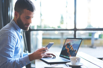 Successful businessman owner of company waiting for phone call from financial manager reporting about signing new beneficial contract while taking data base in laptop computer connected to wifi