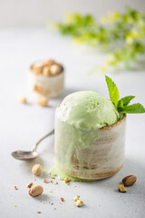 Homemade pistachio ice cream scoop with chopped pistachios on white background