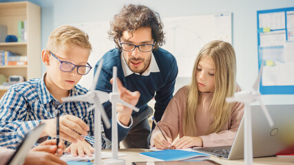 Elementary School Classroom: Enthusiastic Teacher Holding Tablet Computer Explains Lesson to Brilliant Young Children. Kids Learning Programming Languages, Internet Safety and Information Technology