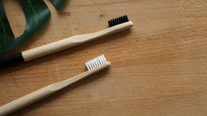 Eco-Friendly bamboo toothbrushes and leaf on a wood background. Natural organic dental concept