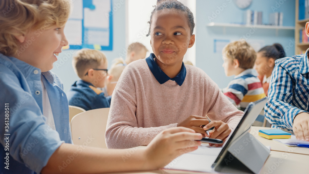 Wall mural in the elementary school: girl and a boy work as a team using tablet computers, learning programming