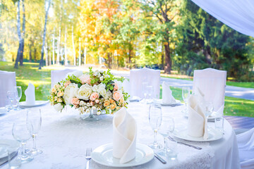 Wedding table with white tablecloth, outdoor setting, view of autumn bright yellow and orange trees