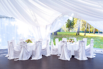 Wedding simple outdoor table setting in a white outdoor tent.
