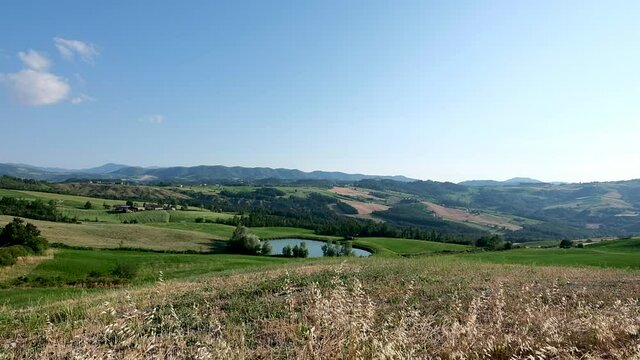View of the Oltrepò Pavese lands with a small lake and cultivated fields