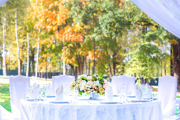Table setting at a wedding reception, outdoor setting, view of autumn bright yellow and orange trees