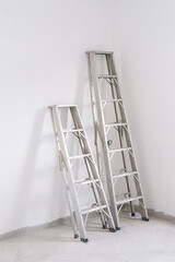 two aluminium stairs ladder lean on white cement wall. high and tall abstract image in construction new house. © Topfotolia