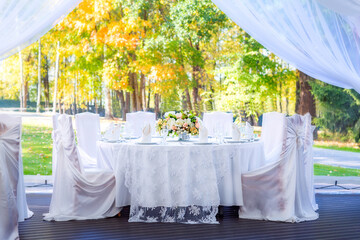 Wedding table with white tablecloth, outdoor setting, view of autumn bright yellow and orange trees