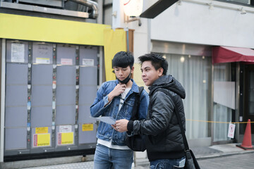 Two young asian man travel in the city and searching the way to visit the famous place