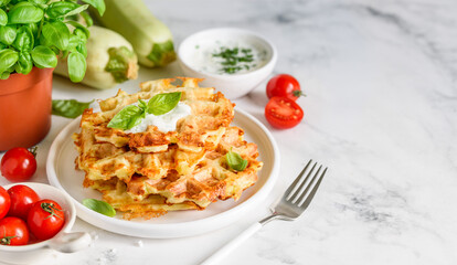Homemade zucchini cheese waffles with sour cream and garlic sauce with dill on a white plate. Copy space.  Selective focus