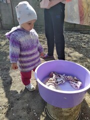 little girl and her mother hanging clothes in yard