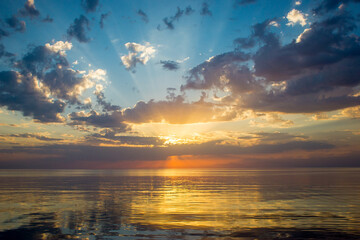 Colorful Sunset sky on the sea. Beautiful evening clouds above the water. Evening seacoast landscape with dusk, sun rays and ocean waves