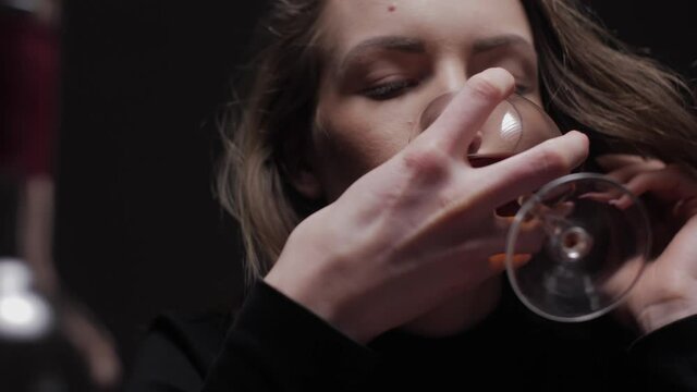 Young beautiful woman in severe depression, drinking alcohol. The concept of abuse and alcoholism. Alcoholic woman with bottle and glass of wine.	
