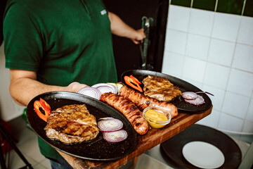 Chef holding prepared meal ready for serving. Grilled pork chop and sausage