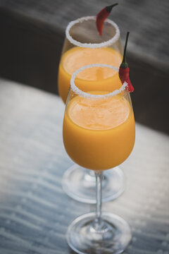 Top Down View Of Cocktail Glasses With Orange, Mango And Red Chilli Exotic Drinks In A British Summer Home Garden. 