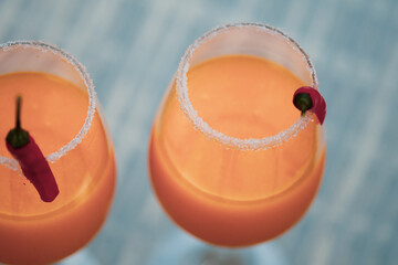Top down view of cocktail glasses with orange, mango and red chilli exotic drinks in a British summer home garden. 