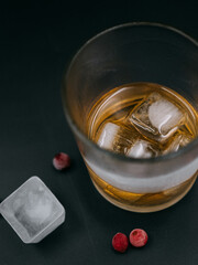 glass of whiskey with frozen berries and ice 
