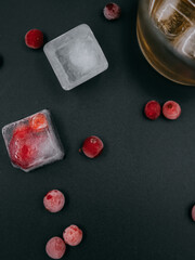glass of whiskey with frozen berries and ice 