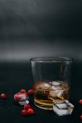 glass of whiskey with frozen berries and ice and smoke around