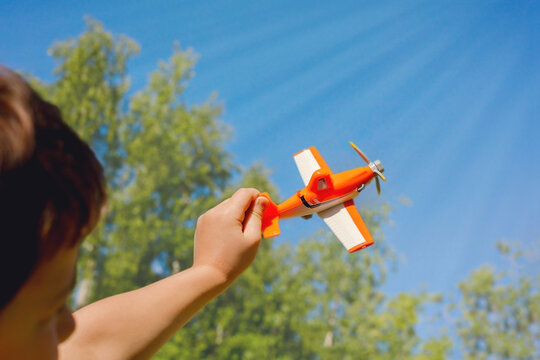 A child's hand holds a plane against the blue sky. Сopy space