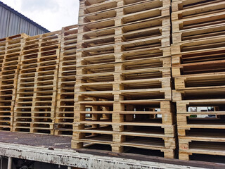 Worker driving forklift truck to unload wooden pallets stack from truck to the cargo warehouse to support shipment for logistics and transportation industry 