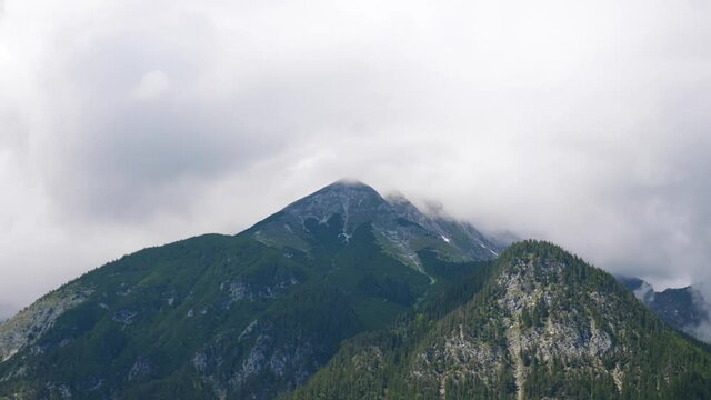 Timelapse of drastic weather changes happening on the peak of a mountain on a cloudy day.