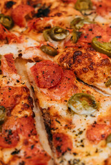 slice of pizza with jalapeño peppers, tomato and salami 