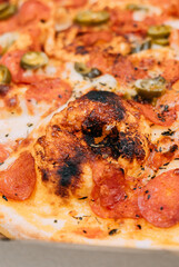 slice of pizza with jalapeño peppers, tomato and salami 