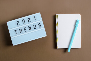 Trend concept 2021, light box with inscription, notebook records, pens, flower.