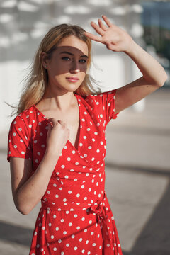Blond young woman on red dress on beach is closed from the sun