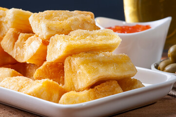 .Fried manioc. Traditional Brazilian food dish. Accompanied by pepper jam, olives and pepper pout. Glass of beer. Selective focus.