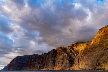 Acantilado rocoso junto al mar en el atardecer nublado