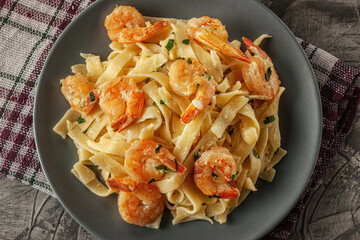 Tagliatelle with prawns and parsley on a gray background