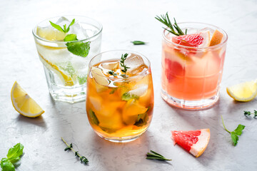 Summer refreshing fruit drinks with ice on a grey background.
