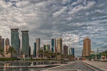 Fototapeta na wymiar Doha, Qatar Skyline daylight view from Sheraton park with reflection in the water and clouds in sky in background
