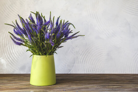 A bouquet of blue Veronica flowers in a green vase. Violet wildflowers copy space.